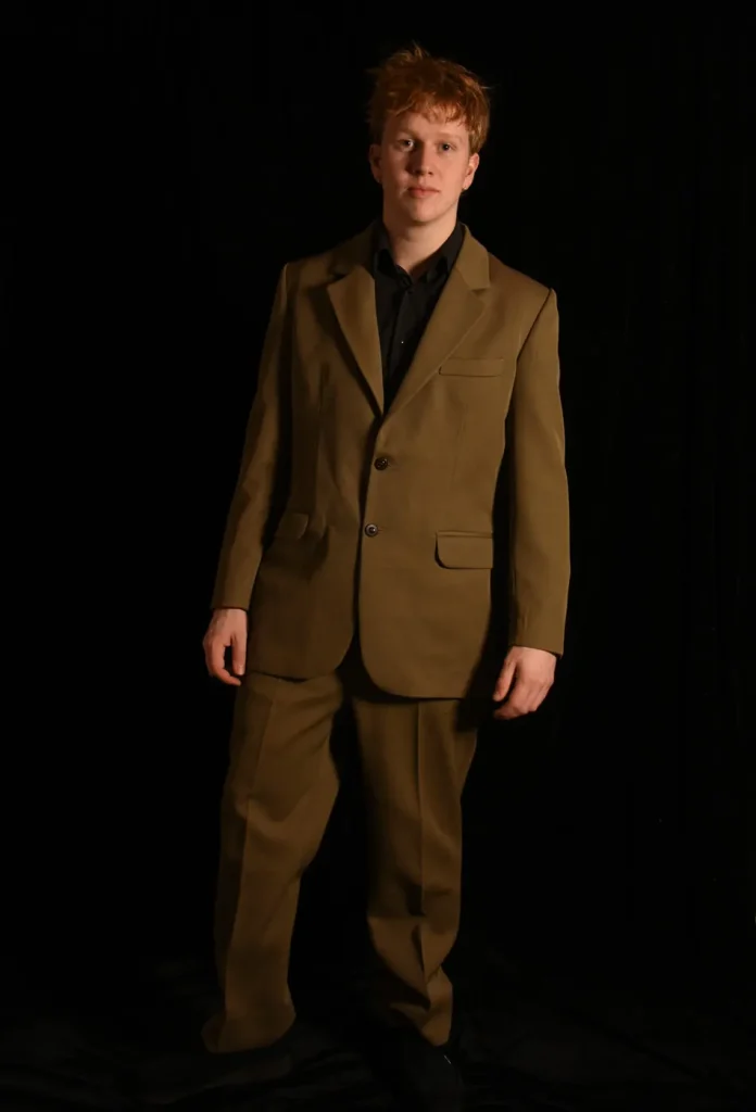Costume marron sur mesure coupé et cousu par Timothé Chevé en stage, porté en studio sur fond noir