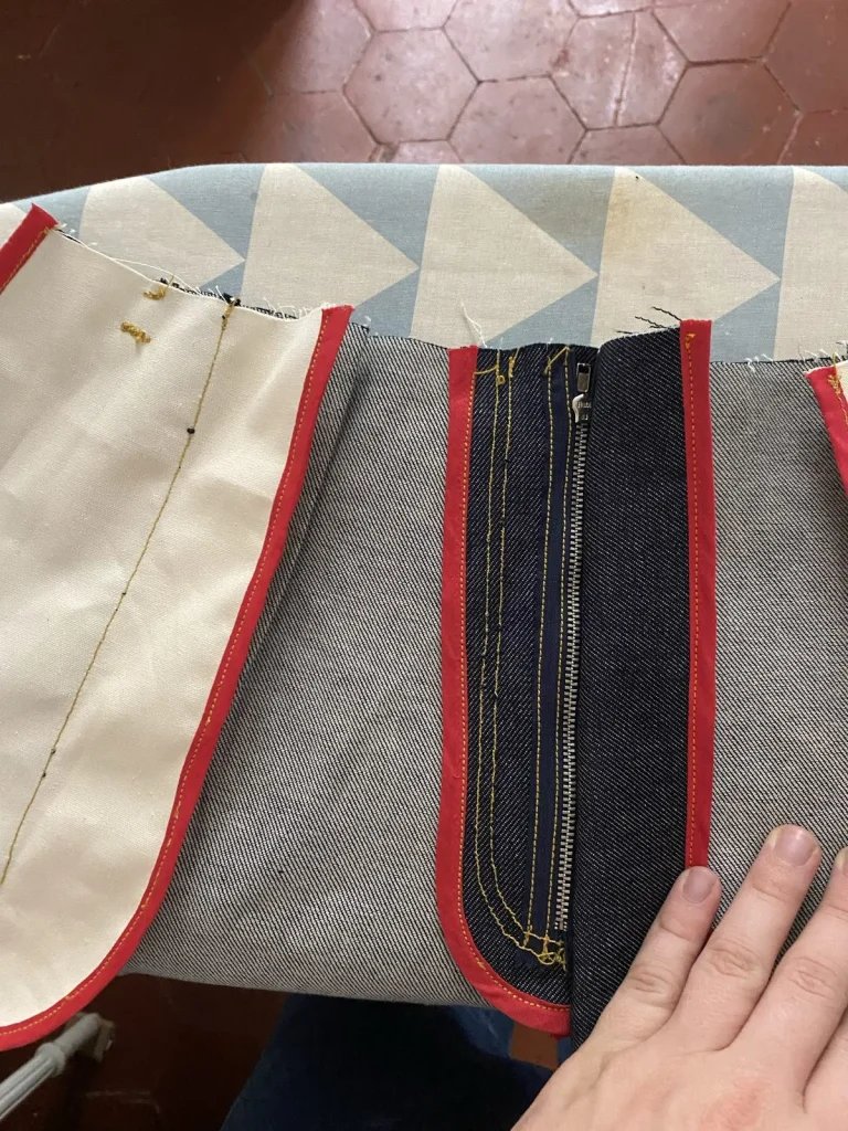 Envers du devant du jean 22BB Timprod : braguette zippée et coutures finies au biais rouge