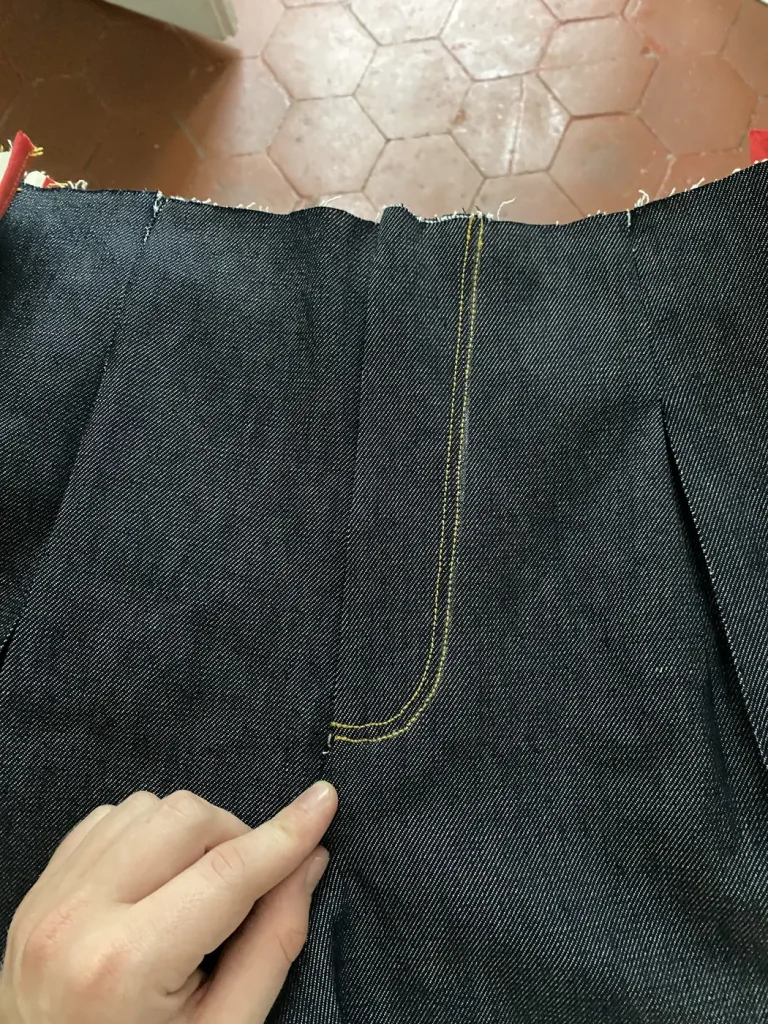 Montage du jean 22BB Timprod : braguette surpiquée de fil jaune et pli de taille sur le denim brut