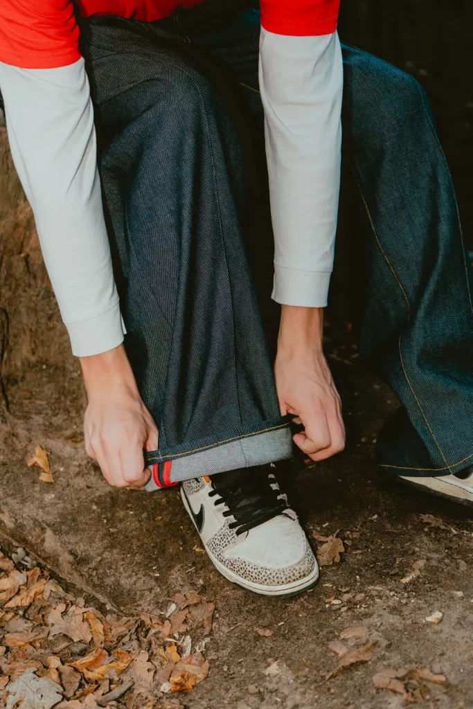 Ourlet du pantalon baggy 22BB Timprod retroussé à la main sur une basket, l’envers clair du denim brut
