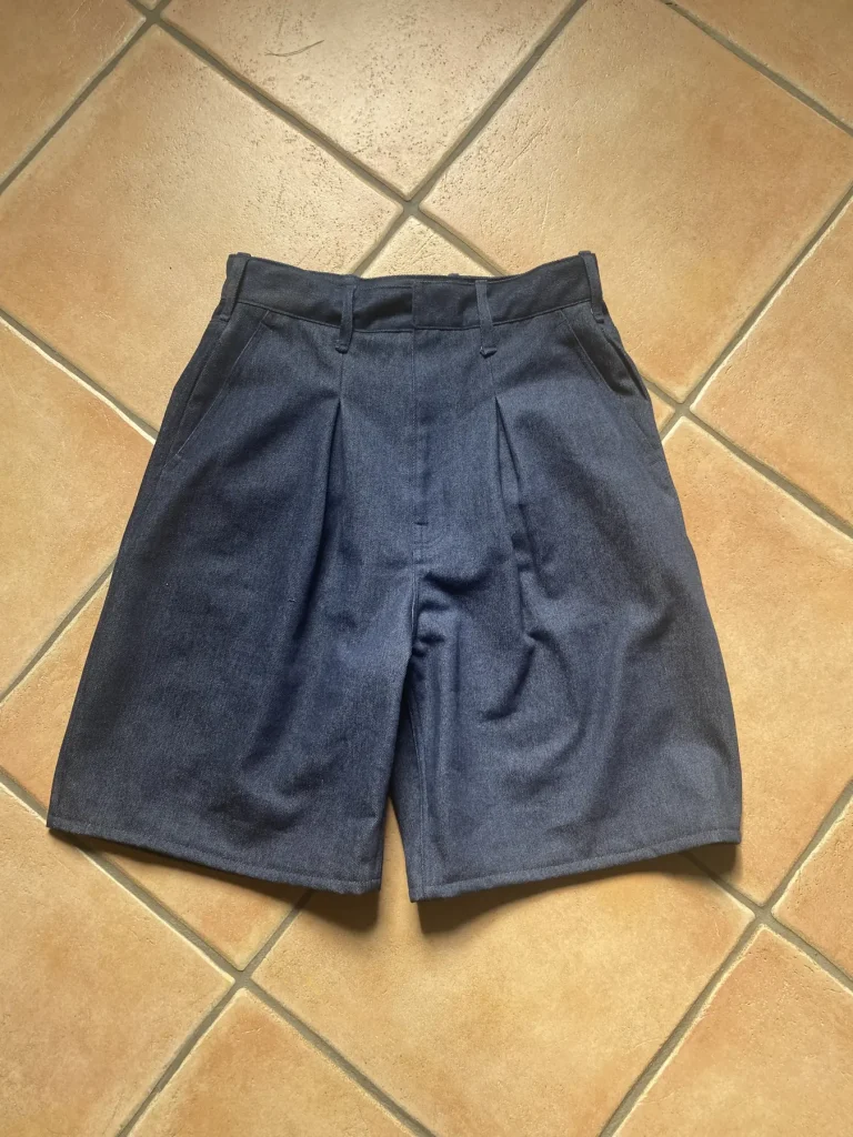 Short Timprod en denim posé à plat sur le carrelage, vu de face : les plis devant et la ceinture