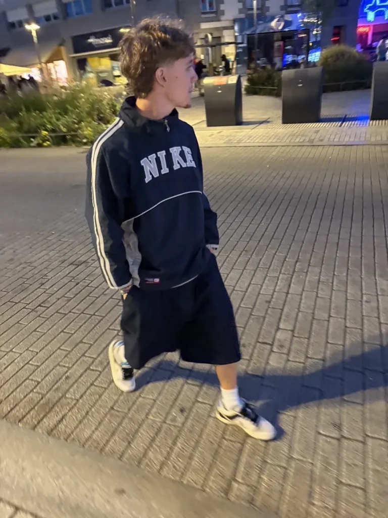 Short Timprod noir porté de nuit dans la rue, avec un sweat et des baskets
