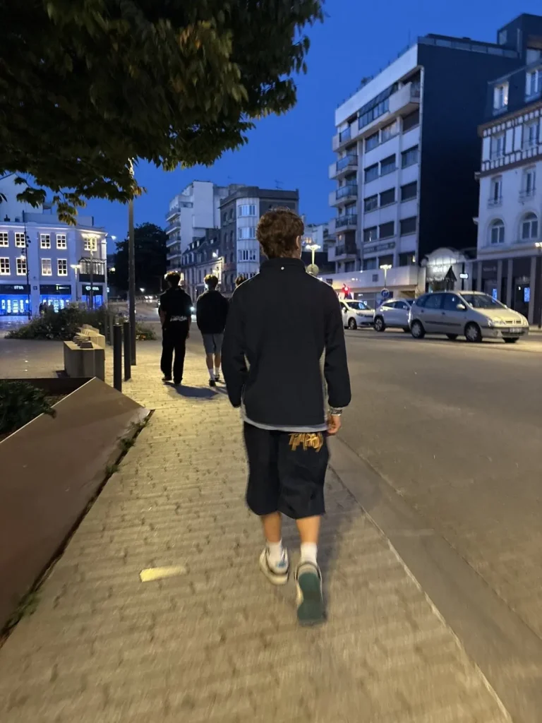 Short Timprod porté de dos dans la rue au crépuscule, logo brodé en jaune sur la poche arrière