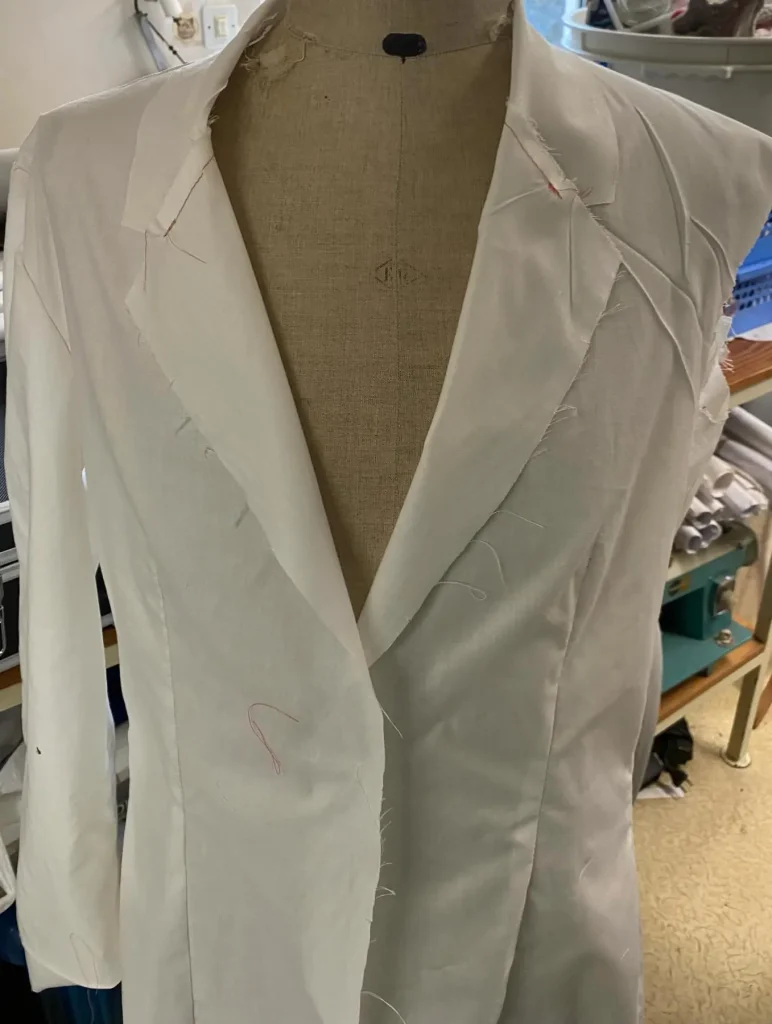 Veste en toile blanche montée sur un mannequin de couture, à l’atelier en janvier 2026