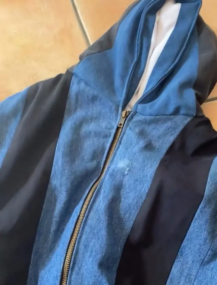 La veste en jeans recyclés terminée, posée à plat : le zip, la capuche et les bandes de denim