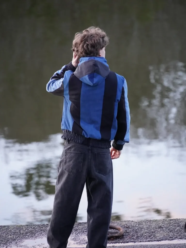 Dos de la veste Timprod en jeans recyclés : bandes verticales de denim bleu et noir jusqu’à la capuche